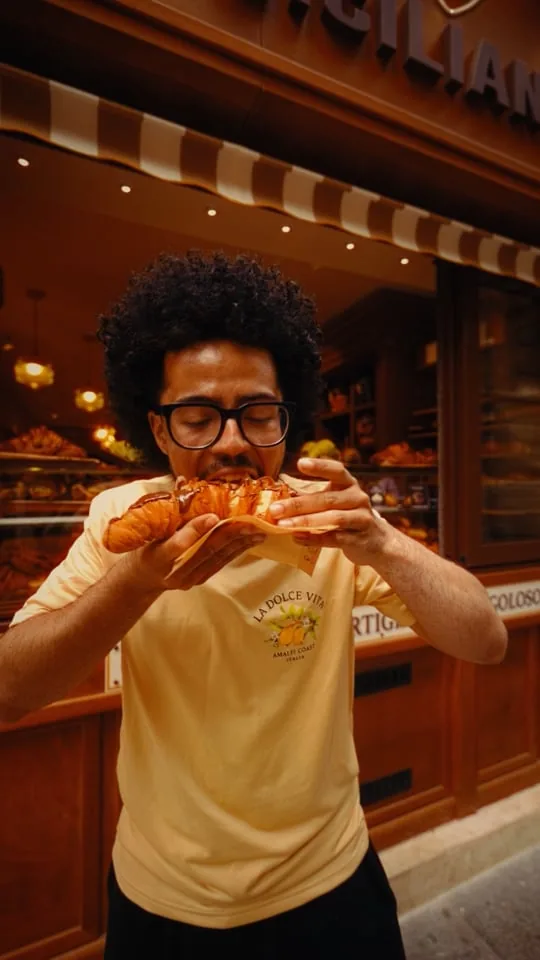 Réel Il Fornaio Siciliano, client dégustant un cannolo devant la boutique